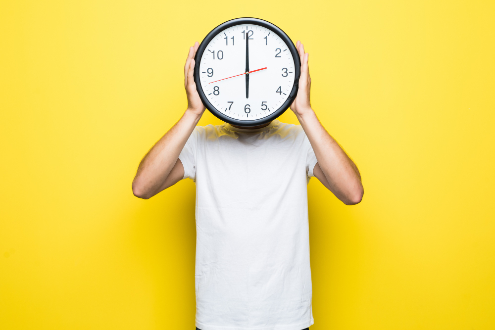 A man showing a clock depicting healthy sleep routine to Prevent Hypersomnia.